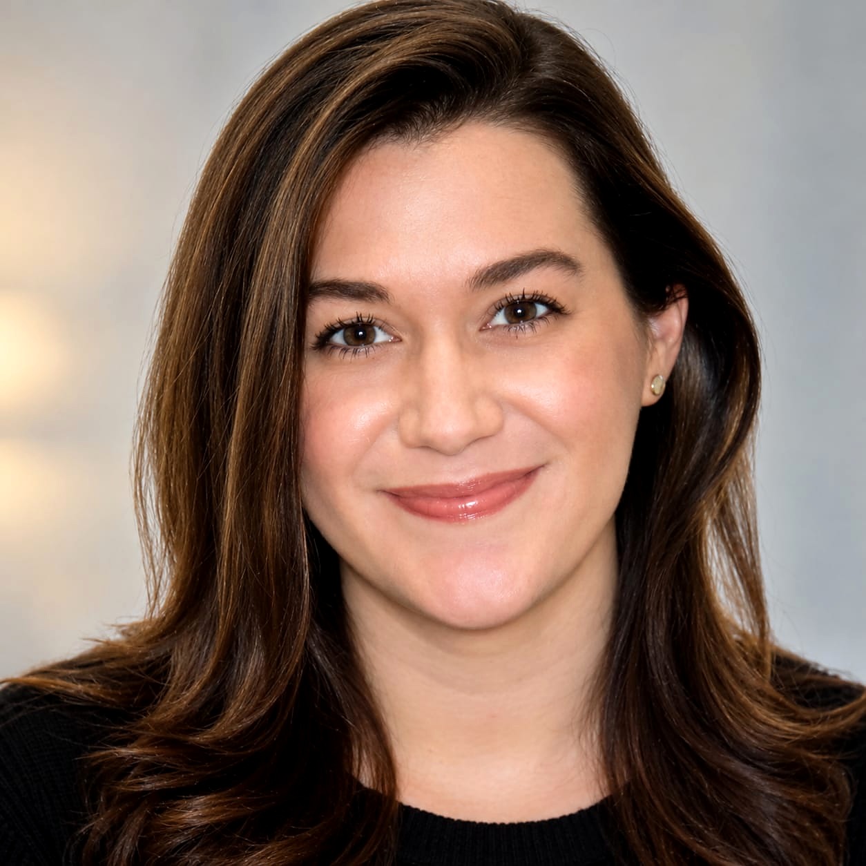 Portrait of Alexandra Kundrat, smiling, with long dark brown hair, wearing a black top